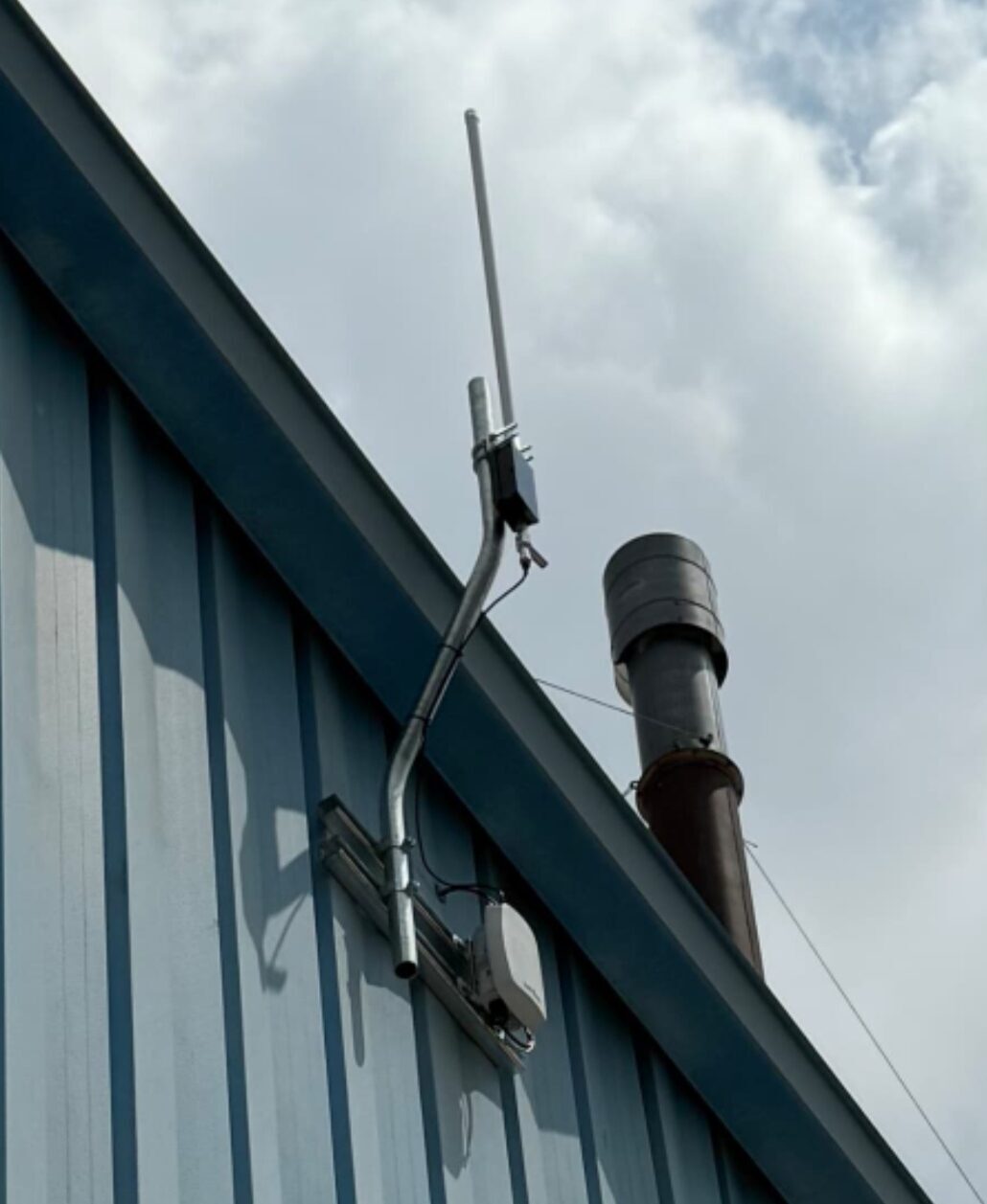 Roof-mounted antenna and gateway on industrial blue metal building